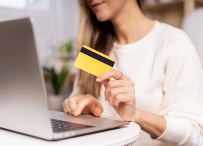 Female on laptop with a bank card in hand