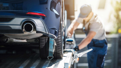 Technicians loading a vehicle onto a trailer to be delivered to a customers house.
