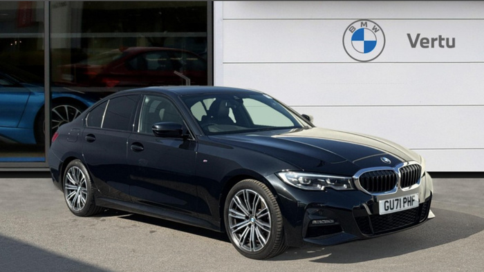 Black BMW sedan parked outside a BMW Vertu dealership, showcasing the front and side view of the car with registration plate GU71 PHF. The dealership features the BMW logo and name Vertu on a white wall. Reflections of other cars are visible in the dealership window, highlighting the availability of used cars and new cars at this location.