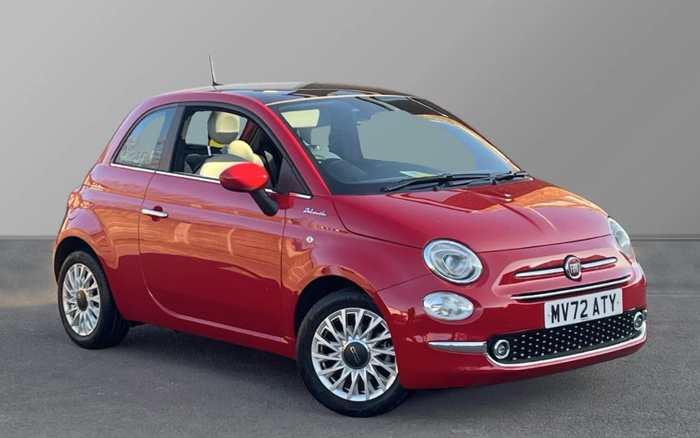 Red Fiat 500 Hybrid car parked on a grey surface with light beige interior and registration plate MV72 ATY, shown from the front side angle against a plain grey background, suitable for used cars and new cars listings.