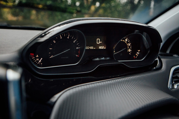 Close-up of a car dashboard showing the speedometer at 0 mph, odometer reading 00486 miles, and trip meter at 1802. The tachometer displays revolutions per minute up to 7 x1000 rpm, and the temperature gauge shows normal engine temperature. The dashboard features a sleek black design inside a vehicle, representing the interior of used cars or new cars.