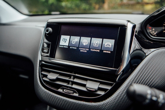 Close-up of a car dashboard infotainment system screen displaying menu options including Radio Media, Settings, Connected Services, Telephone, and Driving. The image showcases the interior design details with air vents below the screen and buttons on the side, highlighting features commonly found in used cars and new cars.