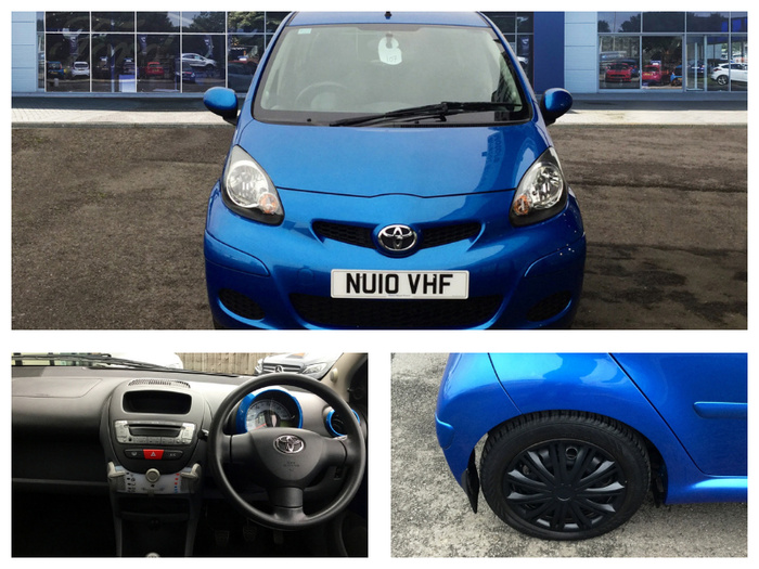 Collage of images showing a blue Toyota Aygo with registration number NU10 VHF, featuring a front view of the car parked outside a dealership with glass windows displaying other vehicles, a close-up of the car's interior dashboard and steering wheel with Toyota logo, and a close-up of the right rear wheel with black hubcap on a gravel surface. Ideal for used cars or new cars buyers.