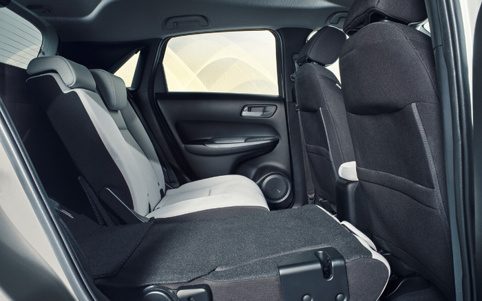 Interior view of a car showcasing rear seats with one seat folded down for extended cargo space, featuring modern upholstery in black and light grey fabric, door panel with silver handle, and rear passenger window highlighting a clean and spacious environment, ideal for buyers interested in used cars and new cars.