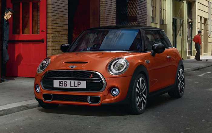 Orange Mini Cooper S parked on a street near a red door and brick building, showing front and side view with license plate 196 LLP. The image relates to used cars and new cars.