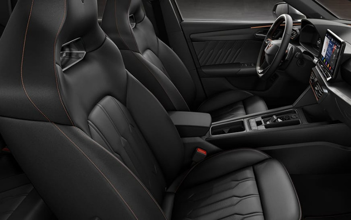 Interior view of a modern car showcasing black leather front seats with orange stitching, a digital dashboard, and a centre console with gear selector and controls, highlighting the sleek and premium design typical of new cars available alongside used cars.