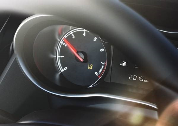 Close-up of a car's tachometer and fuel gauge on the dashboard, showing the engine speed at around 2,300 RPM and an odometer reading of 2015 miles. This image represents used cars and new cars with low mileage.