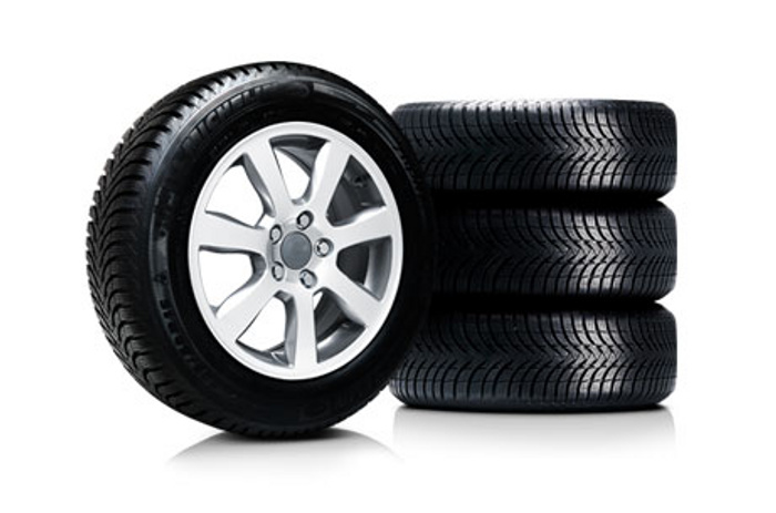 Set of four black car tyres with silver alloy rims, one tyre standing upright showing detailed tread pattern and rim design, three tyres stacked horizontally on a white background, suitable for used cars and new cars.