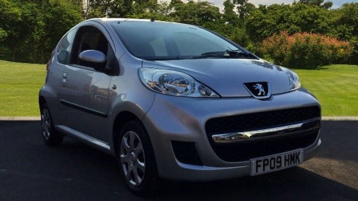 Silver Peugeot compact car parked on a driveway with green grass and trees in the background, showcasing a typical model for used cars and new cars. The car has a UK license plate FP09 HMK and features clear headlamps and a sleek design, ideal for city driving.