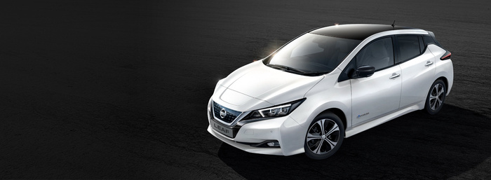 White Nissan LEAF electric car parked on a dark asphalt surface, showcasing modern design with sleek headlights, black roof, and aerodynamic features, representing an option for used cars or new cars.