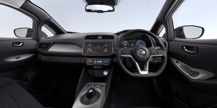 Interior view of a modern Nissan car showcasing the dashboard, steering wheel with Nissan logo, digital instrument cluster, central touchscreen display with radio controls, climate control panel set to 25 degrees, and gear selector. The right-hand drive setup indicates a UK model, highlighting features suitable for used cars and new cars buyers looking for advanced technology and comfort.