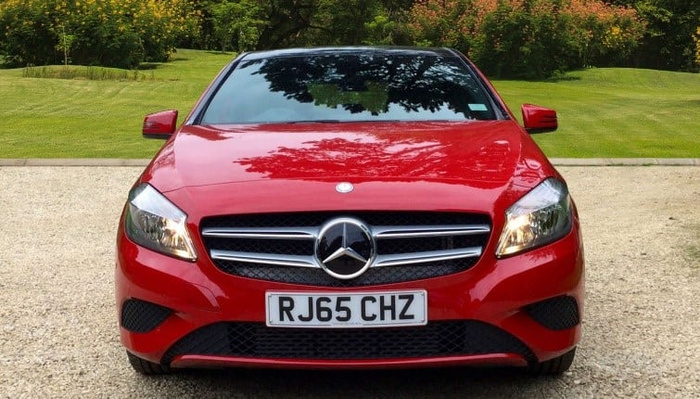 Front view of a shiny red Mercedes-Benz car with registration plate RJ65 CHZ parked on a gravel driveway with green grass and trees in the background, suitable for used cars and new cars listings.