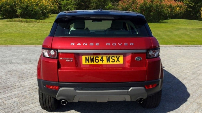 Rear view of a red Range Rover Evoque SD4 with registration plate MW64 WSX parked on a paved driveway with grass and trees in the background, suitable for used cars or new cars advertisement.