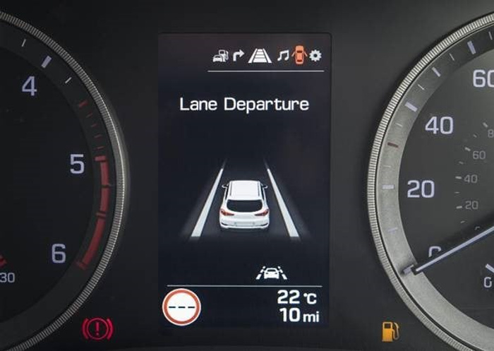 Car dashboard display showing lane departure warning system active with a graphic of a car between two lane lines, text 'Lane Departure', temperature 22°C, and distance 10 miles. Tachometer on the left and speedometer on the right indicating around 0 mph. Warning lights including brake warning and fuel indicator visible. Suitable for used cars and new cars features highlight.