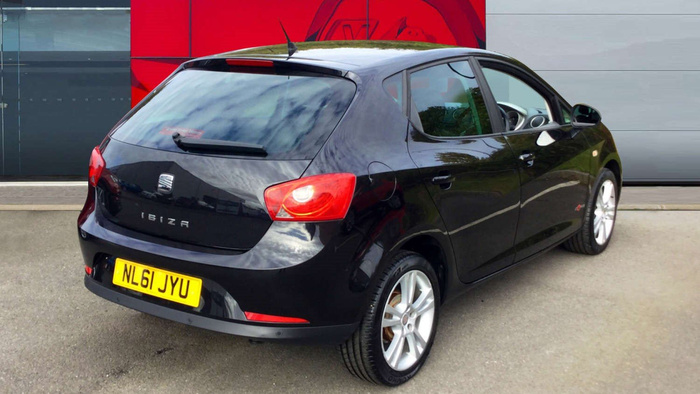 Black SEAT Ibiza hatchback car parked on a driveway in front of a grey and red building, showing rear and side profile, with UK registration plate NL61 JYU, highlighting used cars and new cars options.