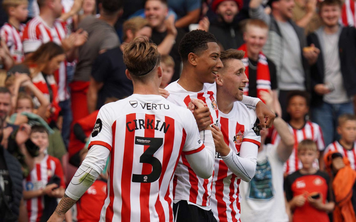 Sunderland AFC football players celebrating on the pitch during a match, wearing red and white striped jerseys with visible names and numbers, including player Cirkin with number 3. The background shows a crowd of excited fans, some wearing matching striped scarves and jerseys. No text or references to used cars or new cars are visible in the image.