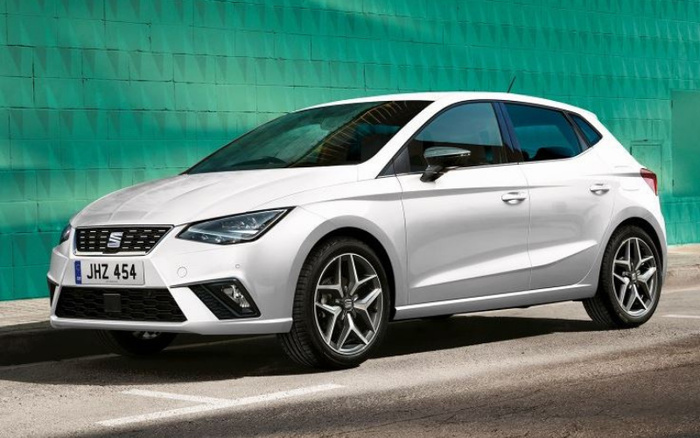 White SEAT Ibiza hatchback car parked on a street with a teal-green geometric patterned wall in the background. The vehicle features modern sharp headlights, sporty alloy wheels, and UK-style number plate JHZ 454. Ideal for buyers searching for used cars or new cars with a compact, stylish design.