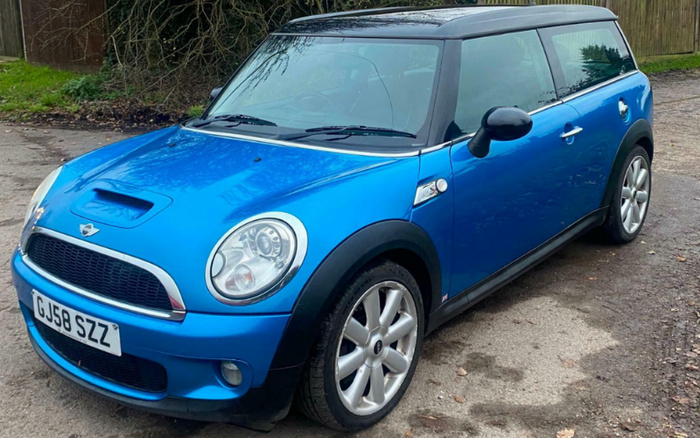 Blue Mini Cooper hatchback parked on a gravel surface with registration plate GJ58 SZZ, featuring black side mirrors and roof, silver alloy wheels, and round headlights, representing a stylish option for used cars or new cars.