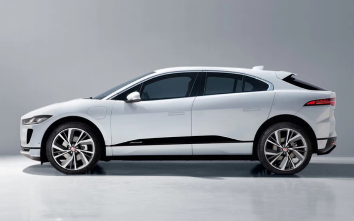 Side view of a white Jaguar I-PACE electric SUV with black detailing, showcased in a studio setting against a plain grey background, highlighting sleek design and modern alloy wheels, ideal for used cars and new cars buyers looking for luxury electric vehicles.