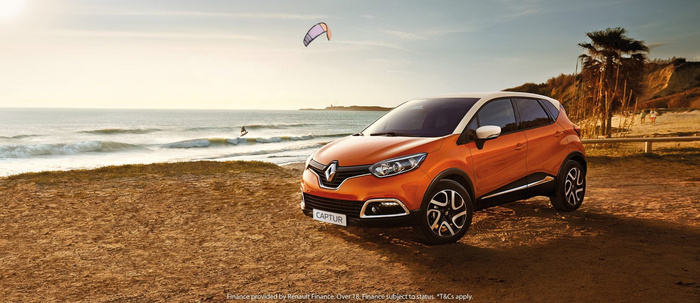 Orange Renault Captur parked on sandy beach near the sea with kite surfer in the background during sunset. Text on number plate reads 'CAPTUR'. Finance disclaimer at bottom states: 'Finance provided by Renault Finance. Over 18. Finance subject to status. *T&Cs apply.' Ideal image for used cars and new cars finance promotions.
