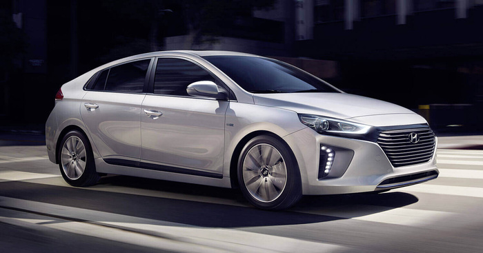Silver Hyundai Ioniq hybrid car driving on a city street, showcasing modern headlights, front grille, sleek aerodynamic design, and alloy wheels, ideal for buyers searching for new cars or used cars.