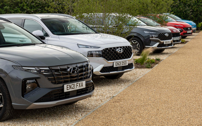 Row of parked Hyundai SUVs in various colours at a dealership, featuring used cars with visible UK registration plates EN21 FXA, EN21 DSO, B6 HYU, EF70 PZN, and EF20 FWH, set on gravel and a paved path surrounded by greenery, showcasing both used cars and new cars available for sale.