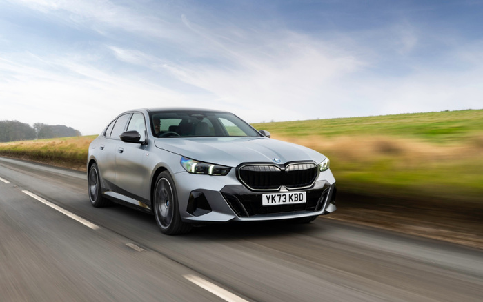 Silver BMW sedan with registration plate YK73 KBD driving fast on a country road with green fields and blue sky in the background, showcasing a new car model ideal for buyers searching for used cars and new cars.