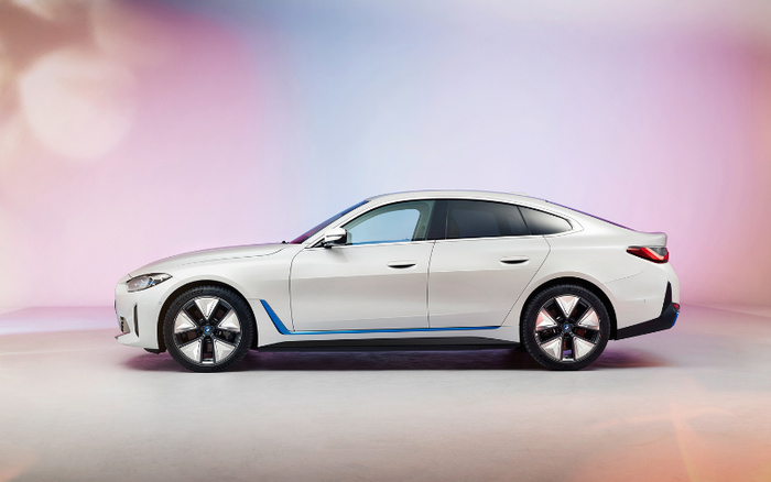 Side view of a sleek white modern sedan car against a soft pink and purple gradient backdrop, highlighting its aerodynamic design, five-spoke alloy wheels, and streamlined body, suitable for illustrating used cars and new cars in automotive sales or reviews.