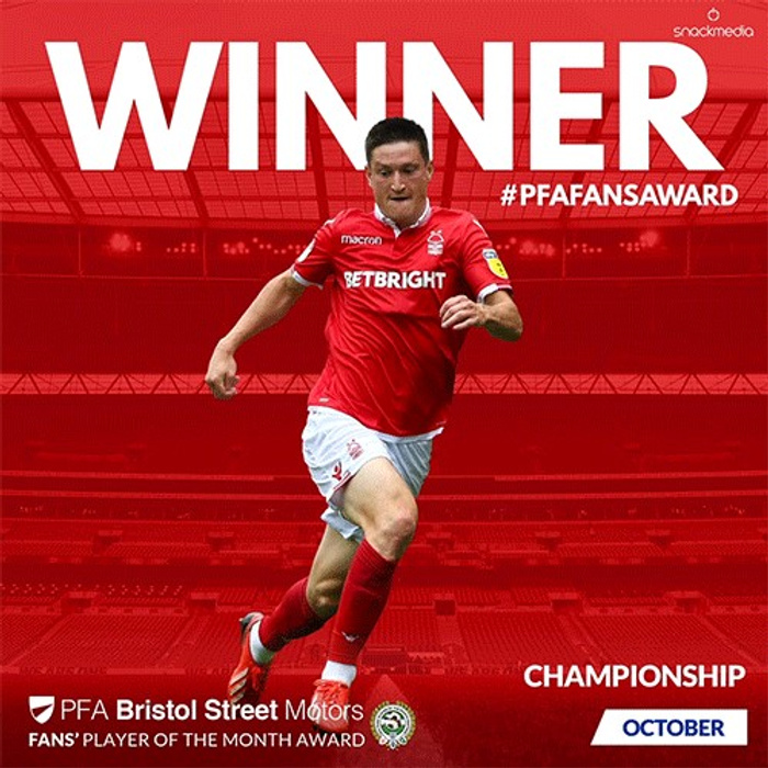 Image featuring a football player in a red kit with white shorts running on a football pitch. The text reads WINNER #PFAFANSAWARD with details about the PFA Bristol Street Motors Fans' Player of the Month Award for the Championship in October. The image promotes the award sponsored by Bristol Street Motors, a dealership associated with used cars and new cars.