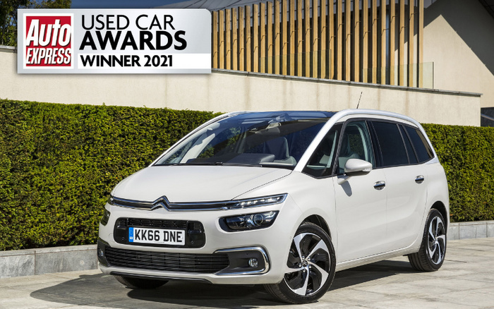 White Citroën car parked in front of a hedge and modern building, featuring a UK license plate KK66 DNE. Image includes a banner in the top left corner with text 'Auto Express Used Car Awards Winner 2021'. The scene highlights a used car, relevant for used cars and new cars categories.