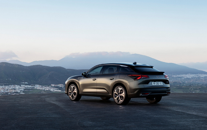 Modern grey electric SUV car parked on an open road with a mountainous landscape and town in the background, showcasing a sleek design and license plate VM-080-VX, ideal for advertising used cars and new cars.