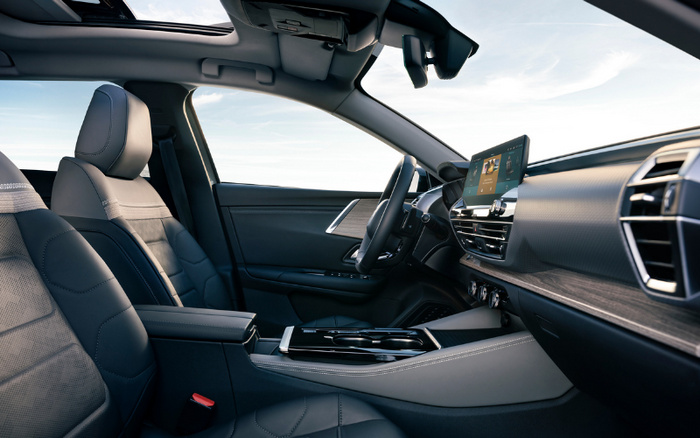 Interior view of a modern car showcasing the driver's seat, steering wheel, and dashboard with a digital touchscreen display. The car features black leather seats with detailed stitching, a panoramic sunroof, and a sleek centre console with cup holders. This image is ideal for advertising used cars and new cars, highlighting the high-quality, contemporary design and advanced technology of the vehicle.