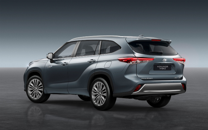 Rear and side view of a grey Toyota Highlander Hybrid SUV parked on a shiny floor with a plain grey gradient background, highlighting the sleek design and modern taillights, suitable for advertising used cars or new cars.
