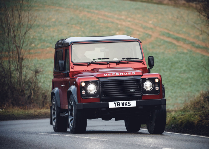 Red Land Rover Defender driving on a country road with licence plate Y8 WKS, suitable for used cars or new cars listings.