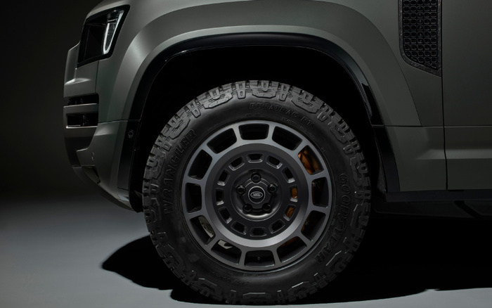 Close-up of a rugged off-road vehicle's front wheel and tire, featuring Goodyear Wrangler Duratrac MT tyres and a Land Rover alloy rim, highlighting the durable design of new cars and used cars suitable for tough terrains.