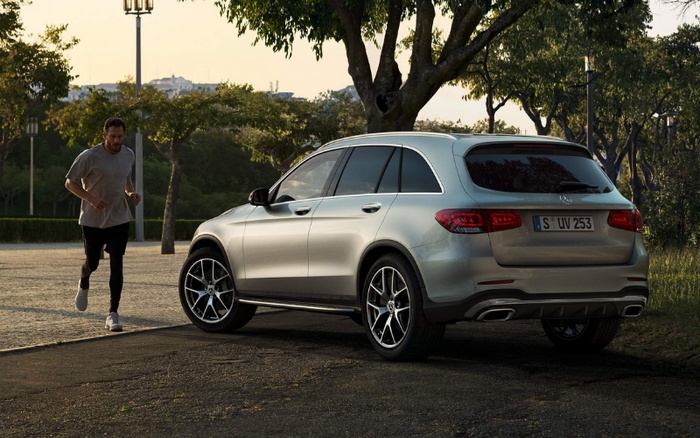 Silver Mercedes-Benz SUV parked next to a park path with a man jogging nearby during sunset, showcasing a modern new car design with details visible on the rear including the license plate S UV 253, ideal for promoting used cars or new cars in an outdoor, lifestyle setting.