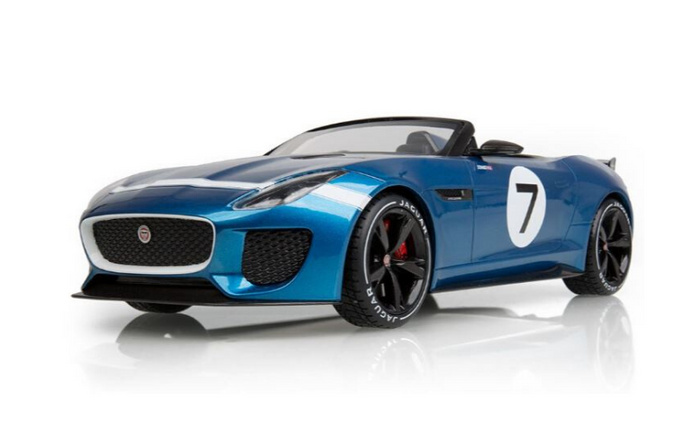 Blue Jaguar convertible sports car with black wheels, red brake calipers, and a white roundel displaying the number 7 on the door, photographed on a white reflective surface, ideal for advertising used cars and new cars.