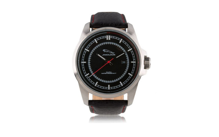 Jaguar branded wristwatch with a black dial, silver case, and black leather strap with red stitching. The watch face displays the Jaguar logo, date at 3 o'clock, and text reading 10 ATM water resistant. The watch is shown on a white background with a reflection below.