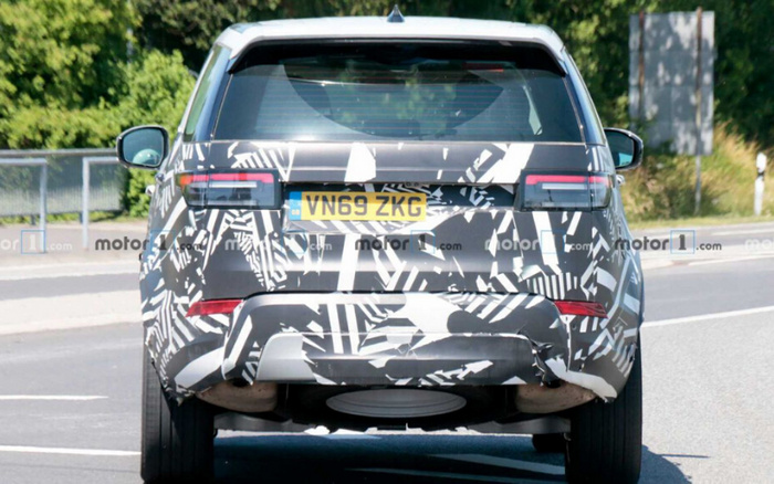 Rear view of a camouflaged prototype car with UK license plate VN69 ZKG, captured on a road during testing, showcasing the vehicle's rear design details which are likely to appear in upcoming used cars and new cars models.