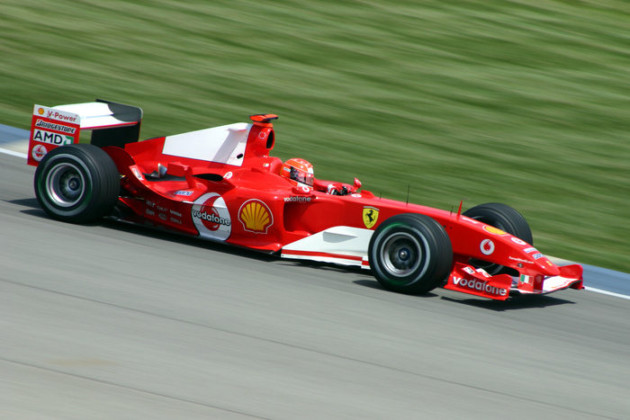 Red Formula 1 race car speeding on a track with visible sponsorship logos including Vodafone, Shell, Bridgestone, AMD, and Ferrari emblem, representing high-performance vehicles akin to new cars and used cars in motorsport.