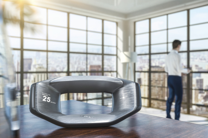 Futuristic metallic car steering wheel with digital displays showing 'FUTURE-TIME INBOUND 25 SECONDS' and a stylised logo, placed on a wooden table in a modern office with large windows overlooking a cityscape, with a blurred man in business attire standing by the windows. Image concept related to used cars and new cars in a futuristic automotive context.