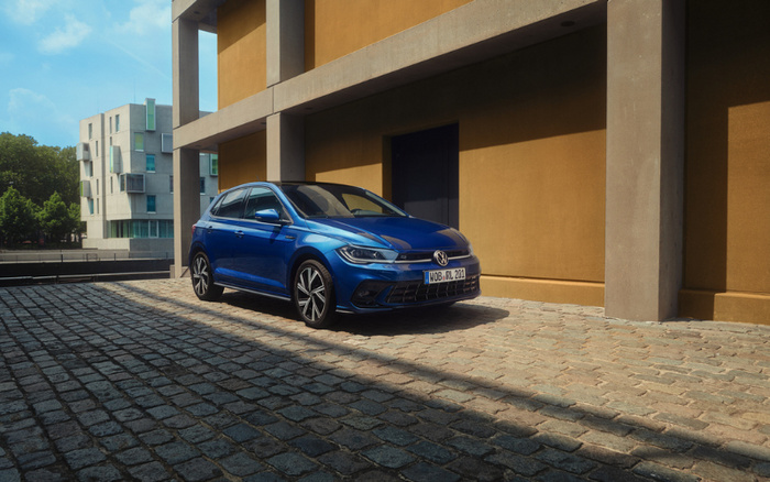 Blue Volkswagen car parked on cobblestone pavement next to a modern yellow and grey building, licence plate reading WOB RL 204. Suitable for used cars and new cars advertisements.