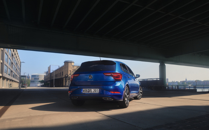 Blue Volkswagen Polo parked under a bridge with city buildings in the background. The car's registration plate reads WOB RL 201. The image represents modern new cars available in urban settings, suitable for those interested in used cars and new cars.