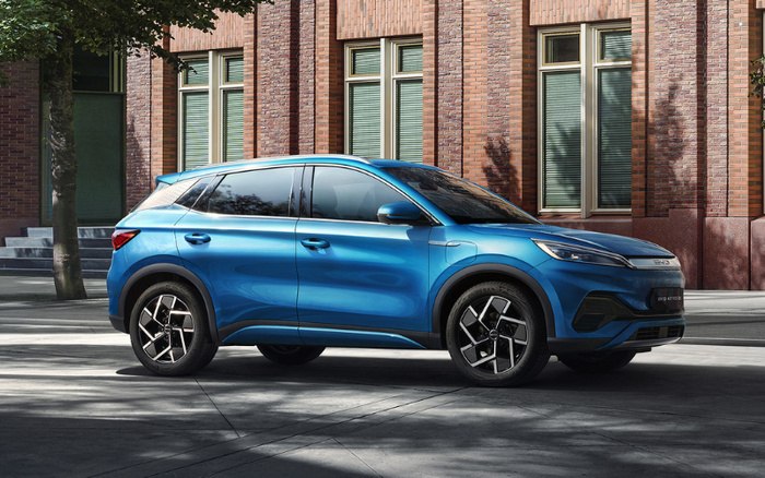Blue BYD ATV 03 electric SUV parked on a city street with modern brick buildings in the background, showcasing sleek design and alloy wheels, suitable for buyers interested in used cars or new cars.