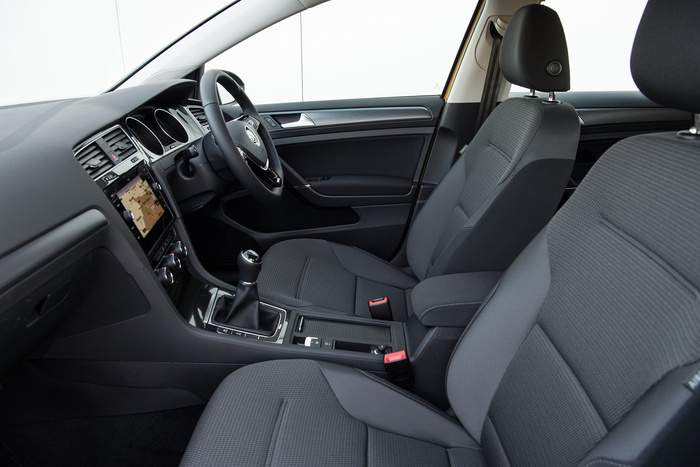 Interior view of a modern car showing front seats, steering wheel, and dashboard with navigation screen. The car has black fabric upholstery and a manual gear stick. This detailed image highlights the clean and contemporary design, suitable for used cars and new cars listings.