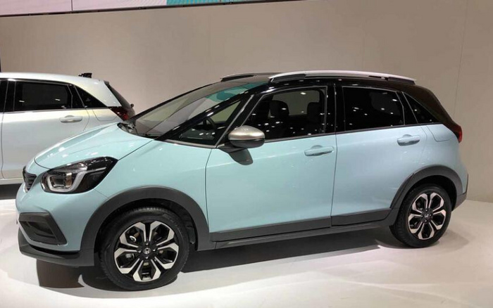 Light blue and black compact hatchback car displayed indoors on a white floor with another white car partially visible in the background, showcasing modern design suitable for new cars and used cars market.