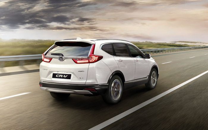 White Honda CR-V SUV driving on a highway during sunset with clear skies, showing rear and side view, featuring CR-V badge and AWD emblem on the back, representing both used cars and new cars.