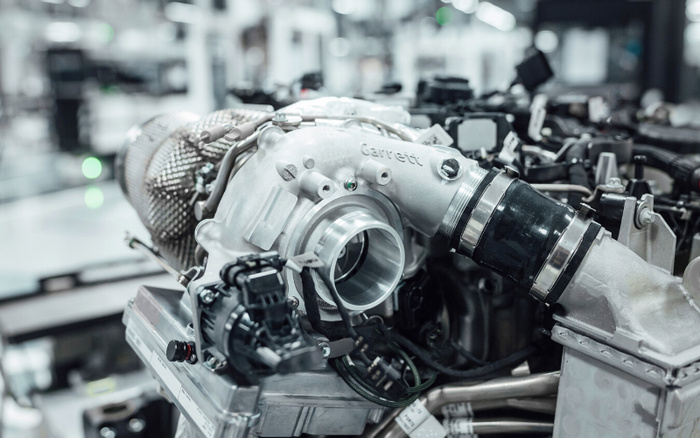 Close-up of a Garrett turbocharger mounted on a car engine in a bright automotive workshop, showcasing intricate mechanical parts and piping, relevant for used cars and new cars maintenance and repair.
