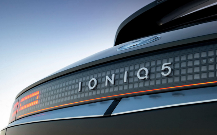 Close-up of the rear of a Hyundai Ioniq 5 electric car showing the illuminated digital light bar with the model name IONIQ 5 in the centre, set against a clear sky background, suitable for used cars and new cars listings.