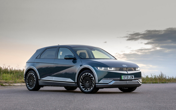 Dark grey Hyundai Ioniq 5 electric car with UK license plate ET21 JZW parked on an open road at dusk, featuring modern rectangular LED headlights and aerodynamic design, suitable as an example of new cars and used cars in automotive sales.